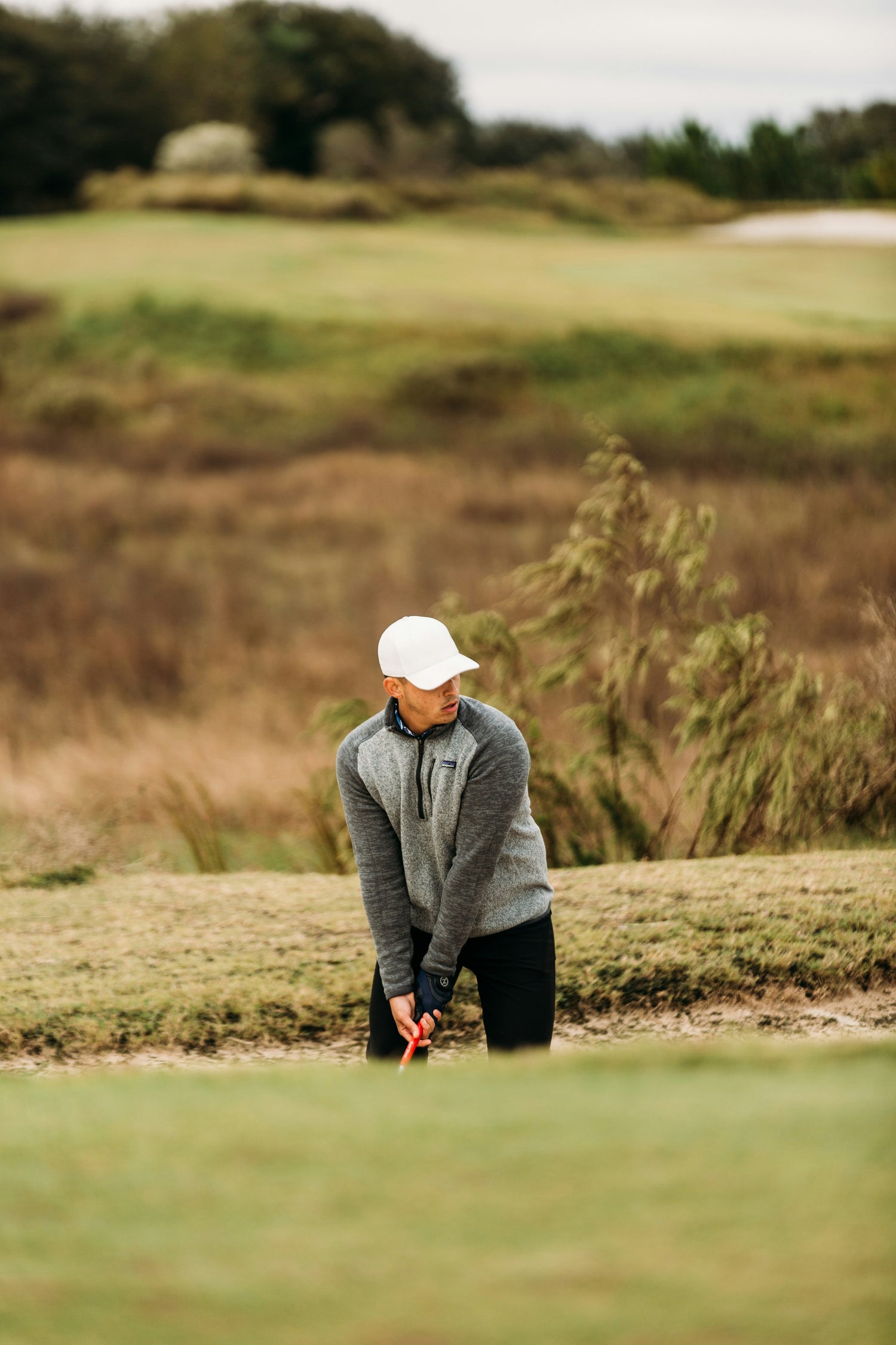 golfer wearing a goodwell golf hat about to go for a swing 